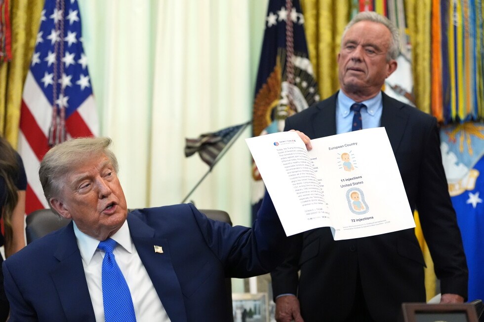 President Donald Trump holds up an image taken from his Truth Social account as Health and Human Services Secretary Robert F. Kennedy Jr. watches during a meeting to sign an executive order about…